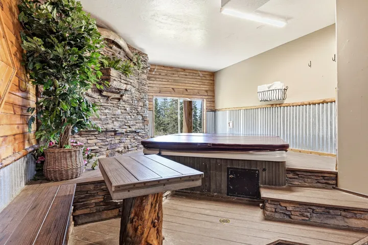 Indoor spa featuring a stacked stone accent wall, wood-finish paneling, corrugated metal wainscoting, and wood-finish decking