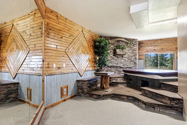 Wood-paneled walls with geometric accents, corrugated metal wainscoting, and a built-in hot tub