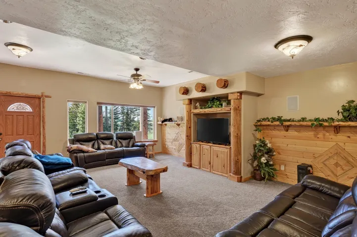 Built-in media center, wood-finish accent wall, ceiling fan, recessed lighting, and large windows