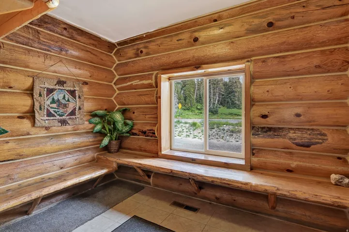 Log wall construction with exposed wood beams, built-in natural wood benches, and a large window