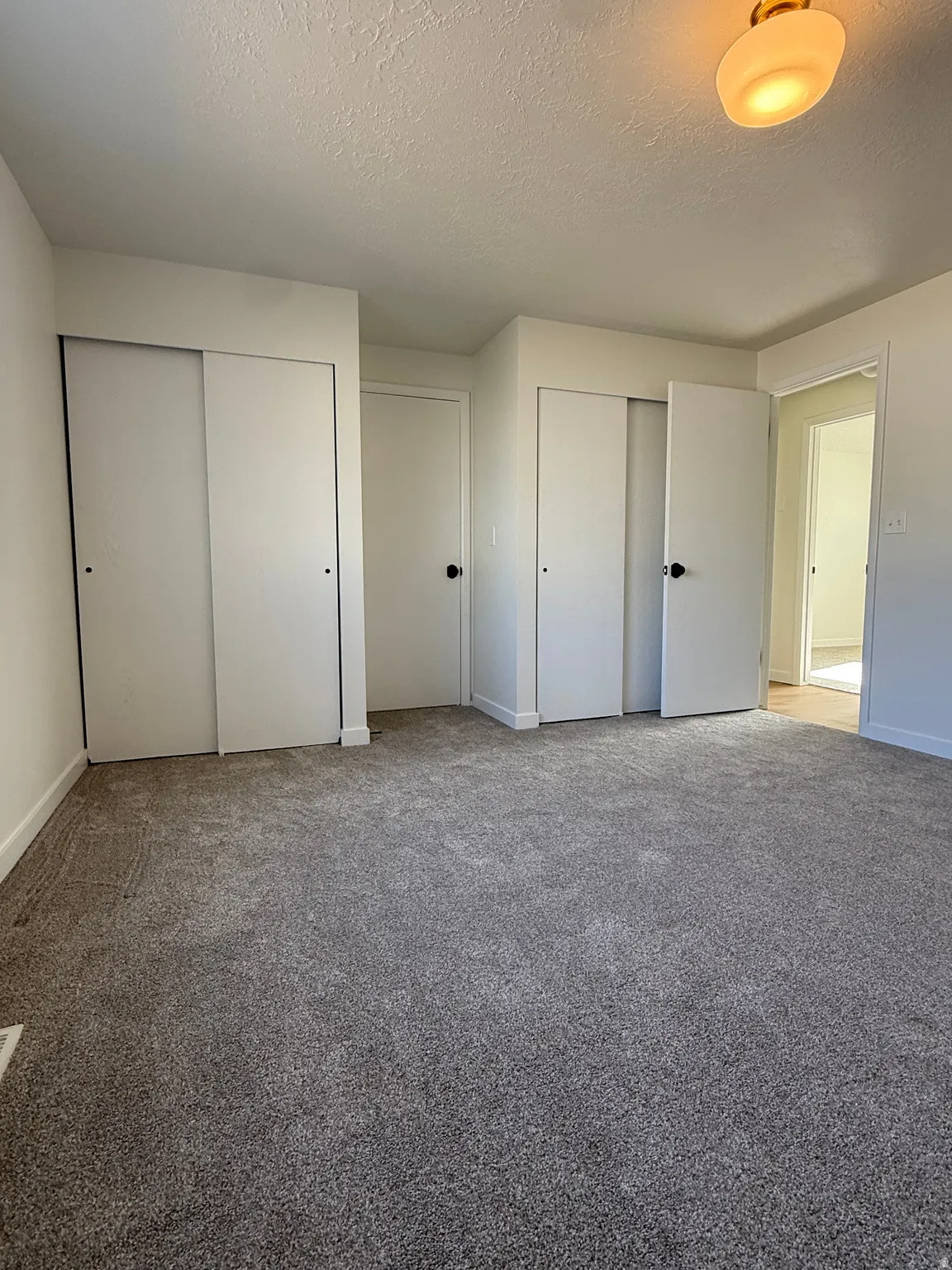 Neutral gray carpeting, white walls, and bright overhead lighting
