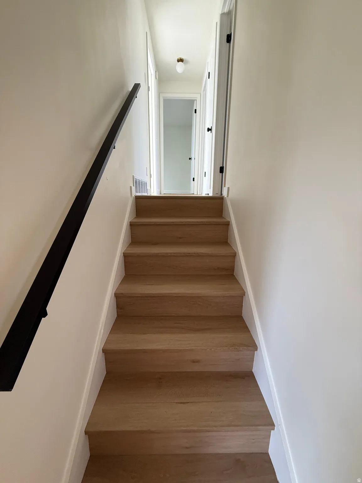 Wood-finish staircase with a matte black handrail