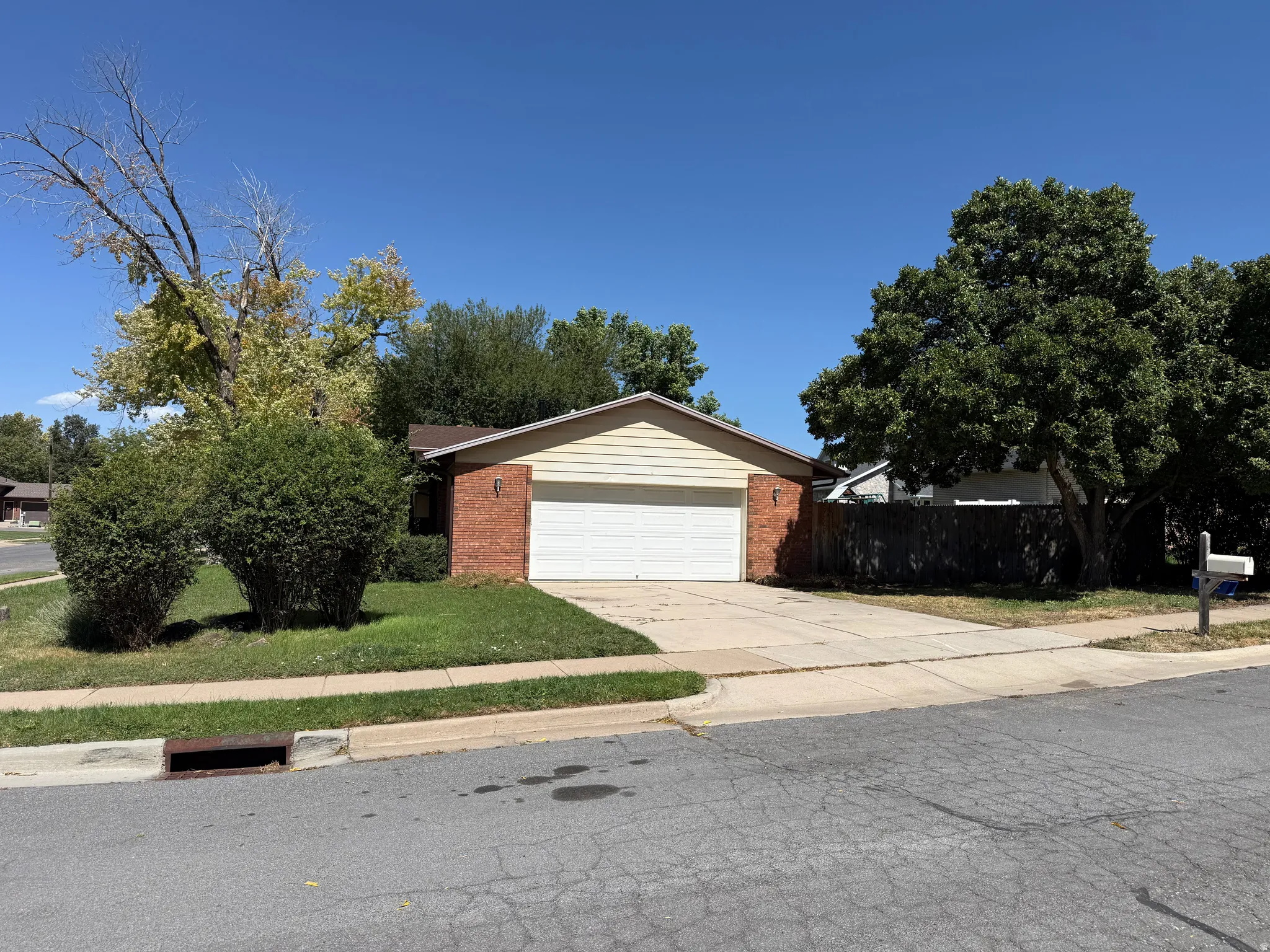Brick and siding exterior with an attached garage, concrete driveway, and mature landscaping