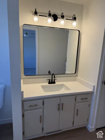 White vanity with gold-tone hardware, rectangular undermount sink, matte black faucet, and coordinating black-framed mirror
