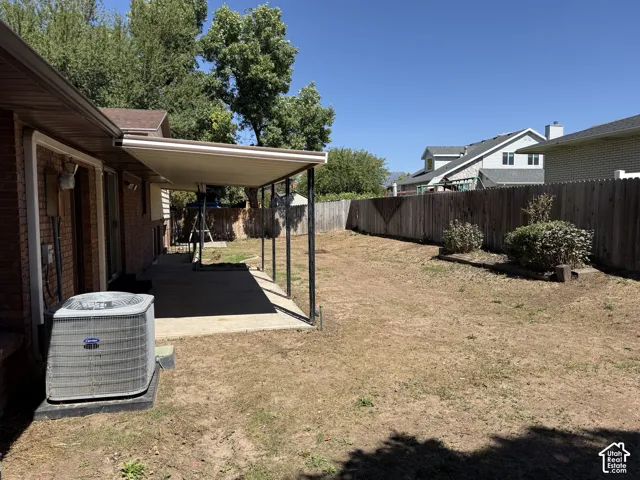 Covered patio with concrete flooring, brick exterior, and a wood privacy fence