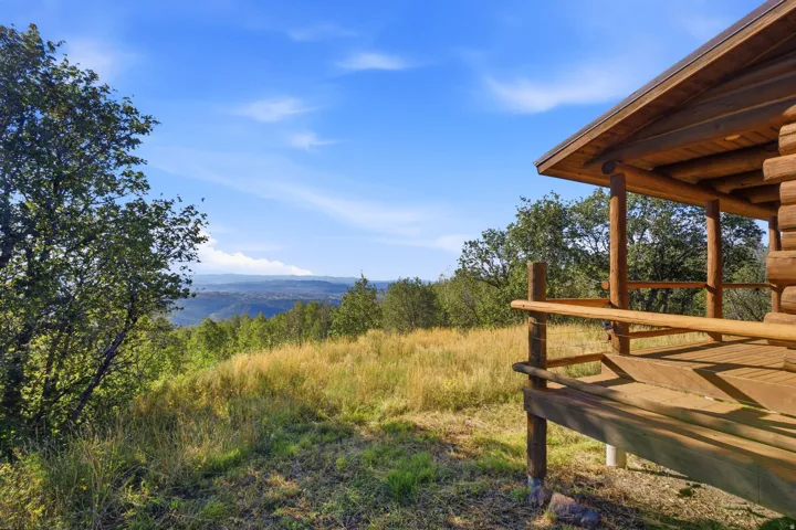 Wood-finish log cabin exterior featuring an expansive wooden porch
