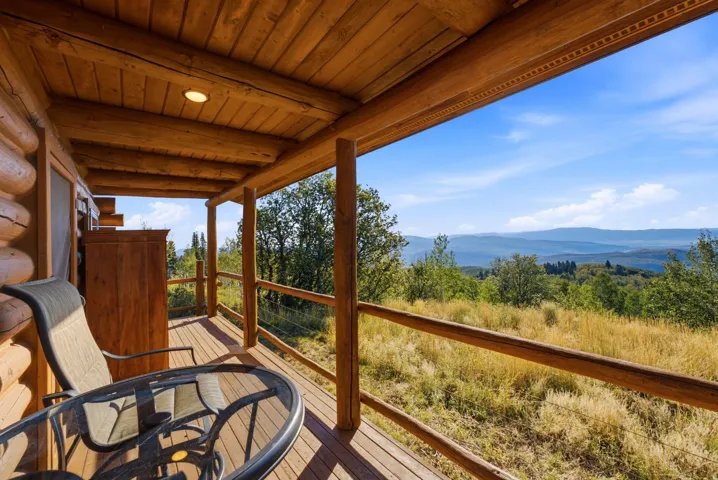 Covered log-style porch featuring a wood-finish deck