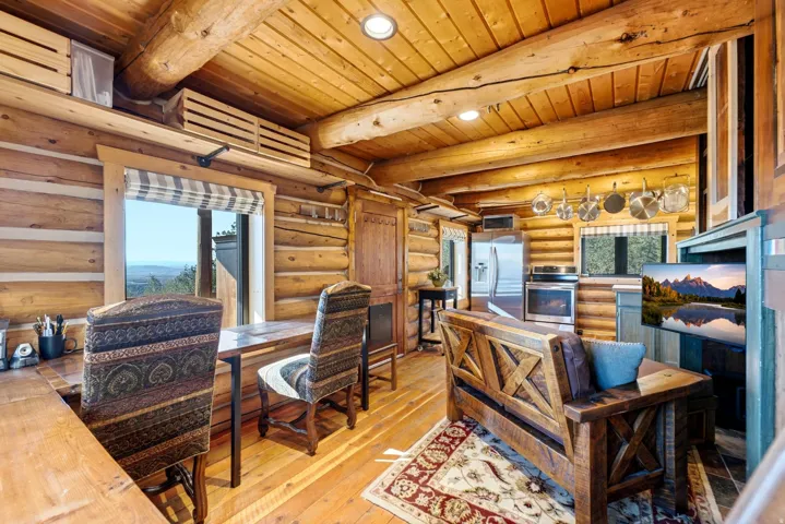 Exposed log construction, wood-finish flooring, recessed lighting, and a stainless steel appliance suite