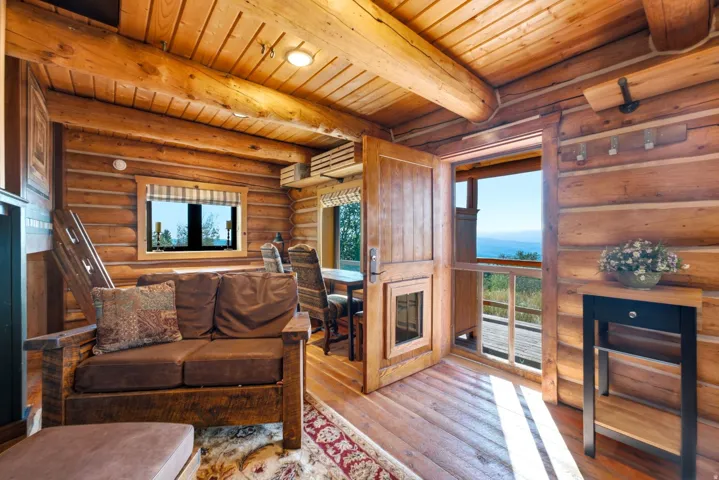 Interior featuring log wall construction, wood-finish ceiling, wood-finish flooring, and a glass-paneled door opening to an exterior deck