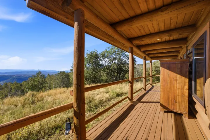 Expansive wood-finish deck with log columns, wood railings, and a wood-paneled ceiling