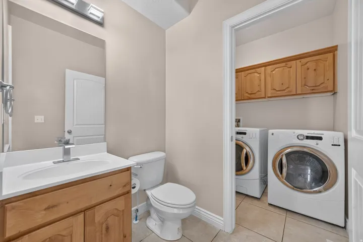 Vanity with wood-finish cabinetry, white countertop, and integrated sink