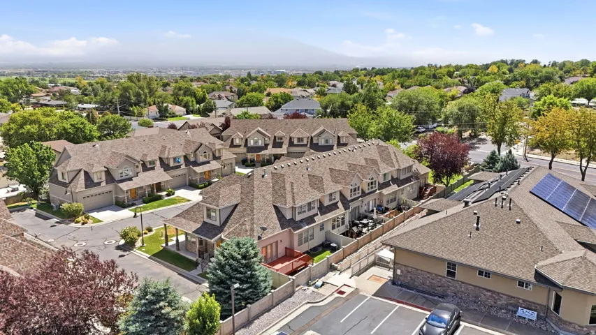 Aerial view of this expansive multi-unit residential complex featuring distinctive peaked rooflines with dimensional shingle work, multiple attached garages, and organized hardscaped driveways