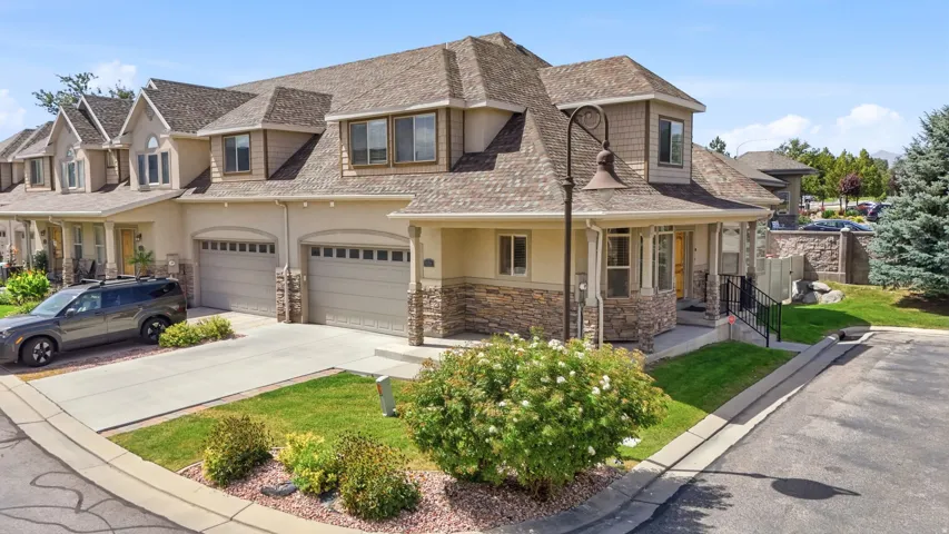 Multi-level exterior with dormer windows, stone accent siding, covered entry, and attached garage