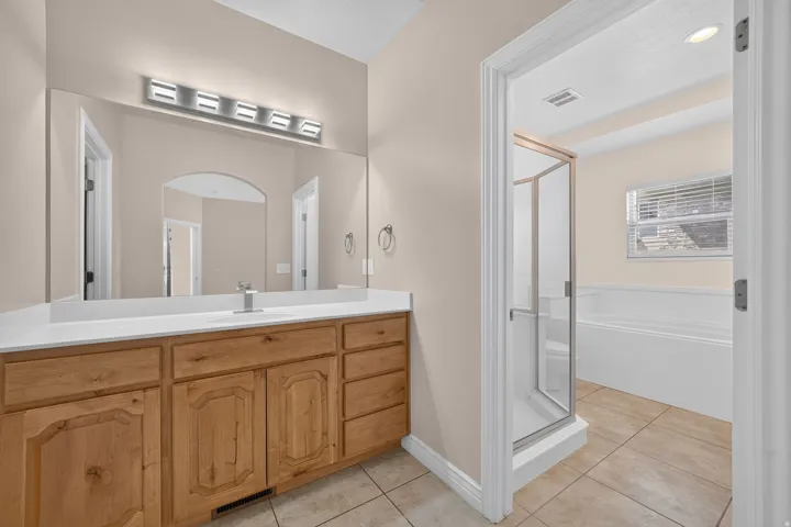 Bathroom featuring a wood-finish vanity with an integrated sink, a large wall mirror, and a modern light fixture