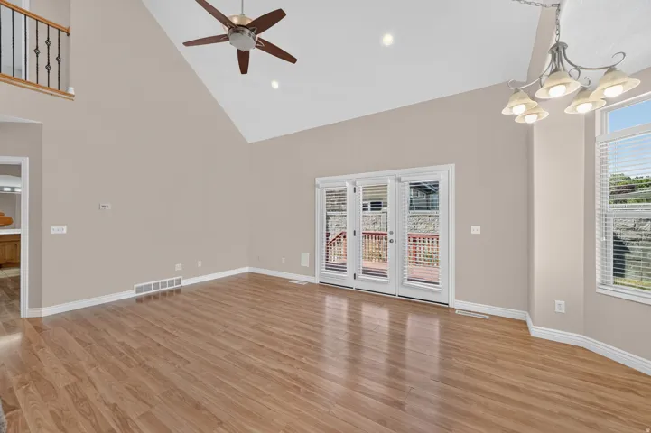 Vaulted ceiling, wood-finish flooring, ceiling fan, recessed lighting, and French doors leading to an outdoor deck