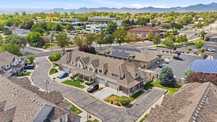Townhome residences with dormer windows, attached garages, and paved driveways