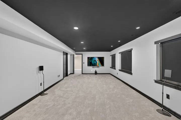 Recessed lighting illuminates the space, featuring a dark ceiling, light-colored walls, and a light gray carpeted floor