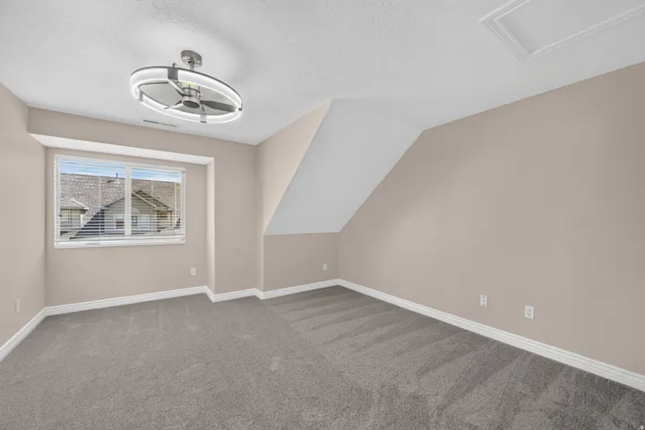 Recessed window with blinds, ceiling-mounted fan with integrated lighting, textured ceiling, and neutral carpet flooring