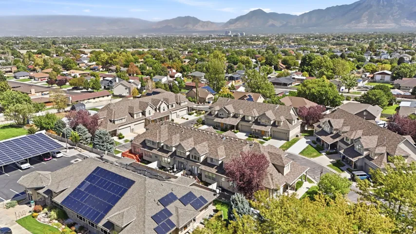 Community setting with mature landscaping, solar panel installations, and distant mountain scenery