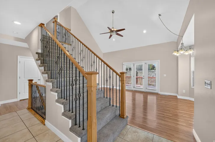 Carpeted staircase with wrought iron balusters and wood handrails, complemented by tile flooring