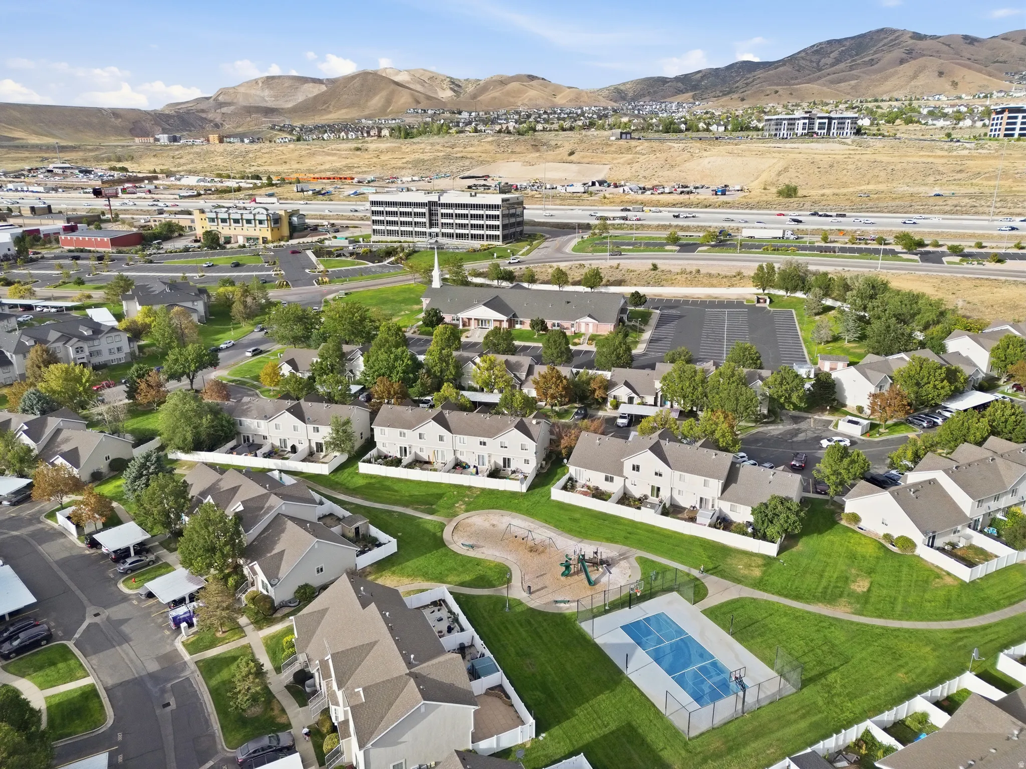 Community green space featuring a playground, multi-sport court, and paved walking paths