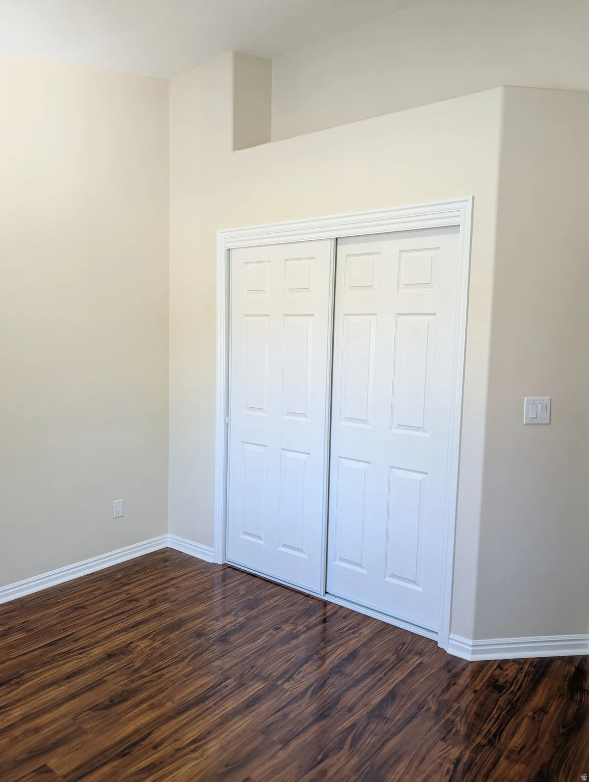 Wood-finish flooring, white paneled closet doors, and light-colored walls