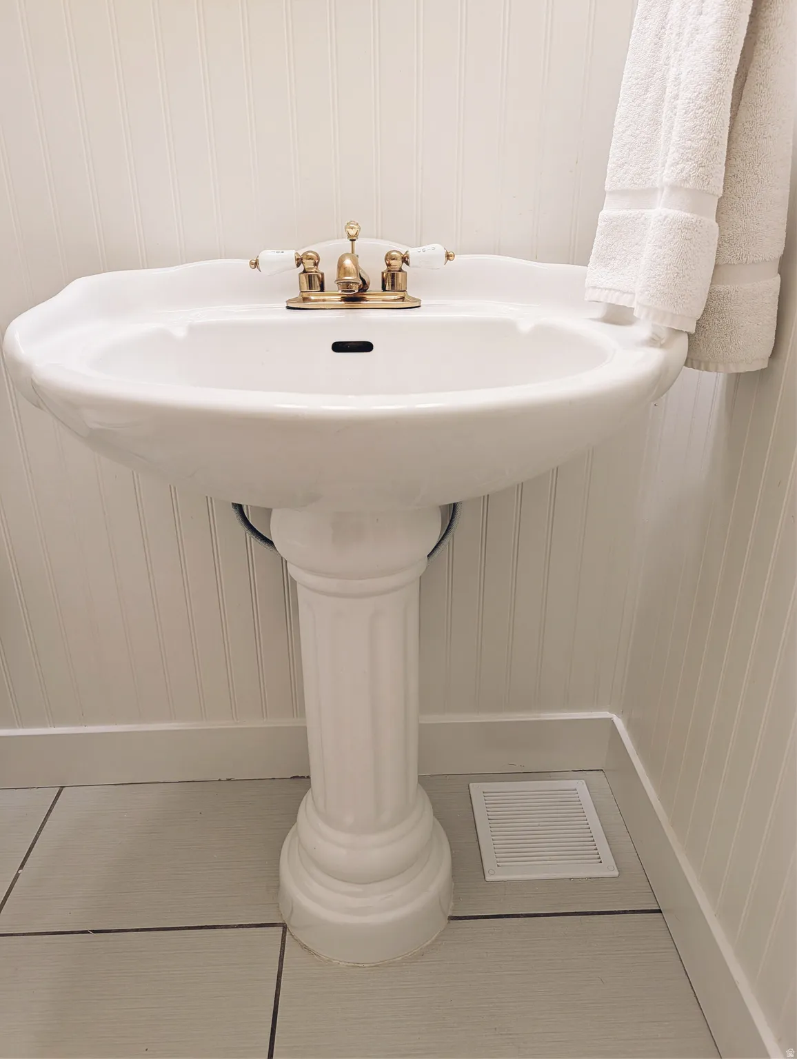 White pedestal sink with a brass-finish faucet.