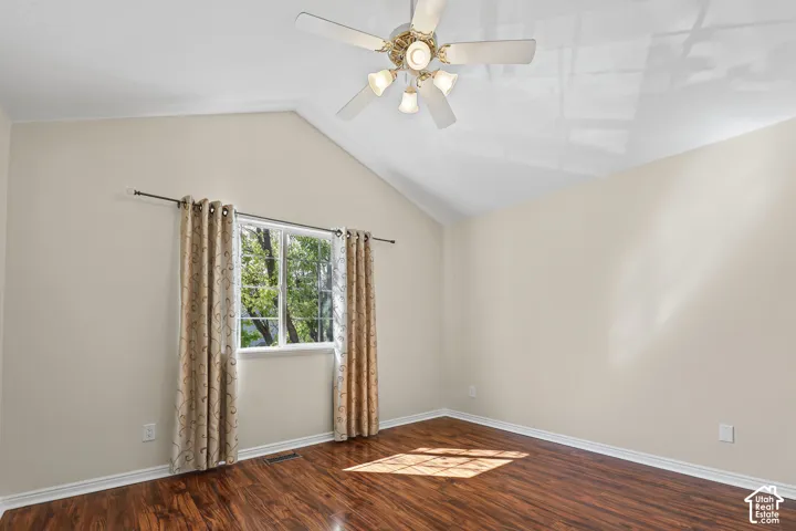 Vaulted ceiling with crown molding, ceiling fan, wood-finish flooring, and a single window