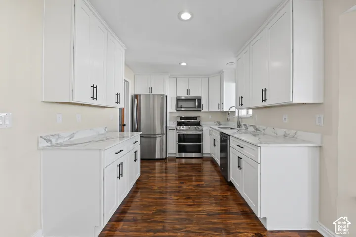 Bright kitchen with white cabinetry, stainless steel appliances, wood-finish flooring, and light-toned countertops