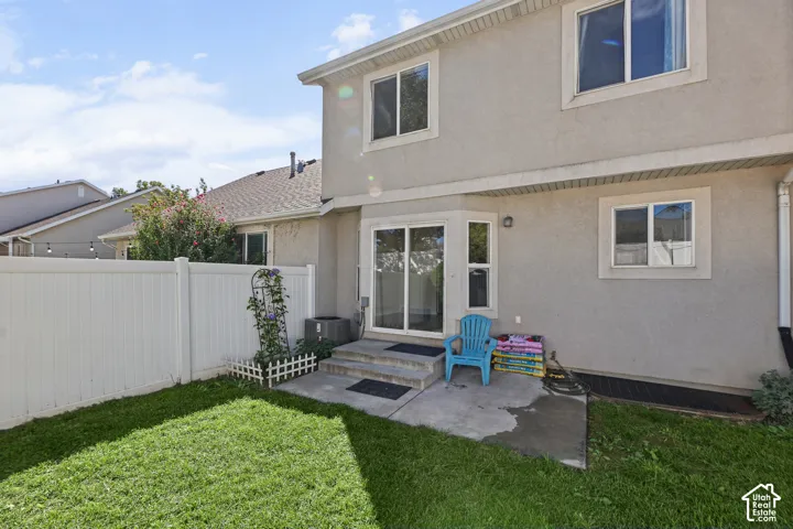 Private backyard with a vinyl fence, concrete patio, and a grass lawn