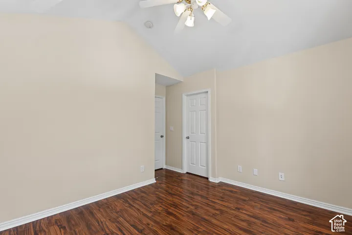 Vaulted ceiling, wood-finish flooring, ceiling fan with integrated lighting, paneled interior doors, light-toned wall finish