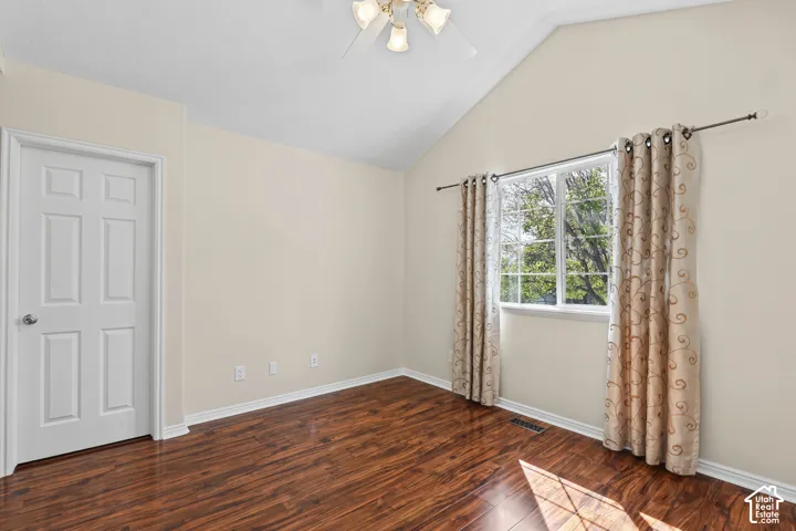 Vaulted ceiling with a ceiling fan, wood-finish flooring, and a multi-pane window