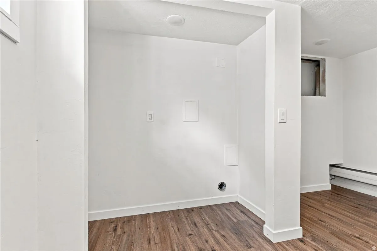 Spacious walk-in closet featuring white framed construction, wood-finish flooring, and abundant natural lighting from recessed ceiling fixtures