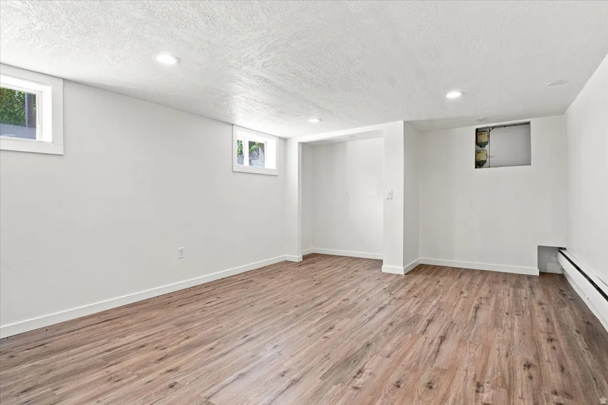 Finished basement featuring wood-finish flooring throughout, recessed ceiling lighting, and multiple windows allowing natural light