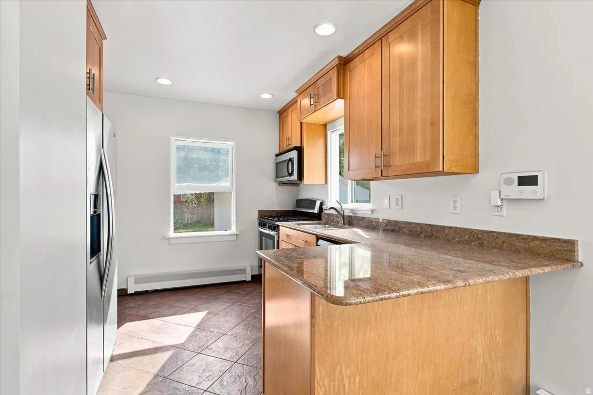 Kitchen featuring wood cabinetry, stainless steel appliances, recessed lighting, and a stone-finish countertop