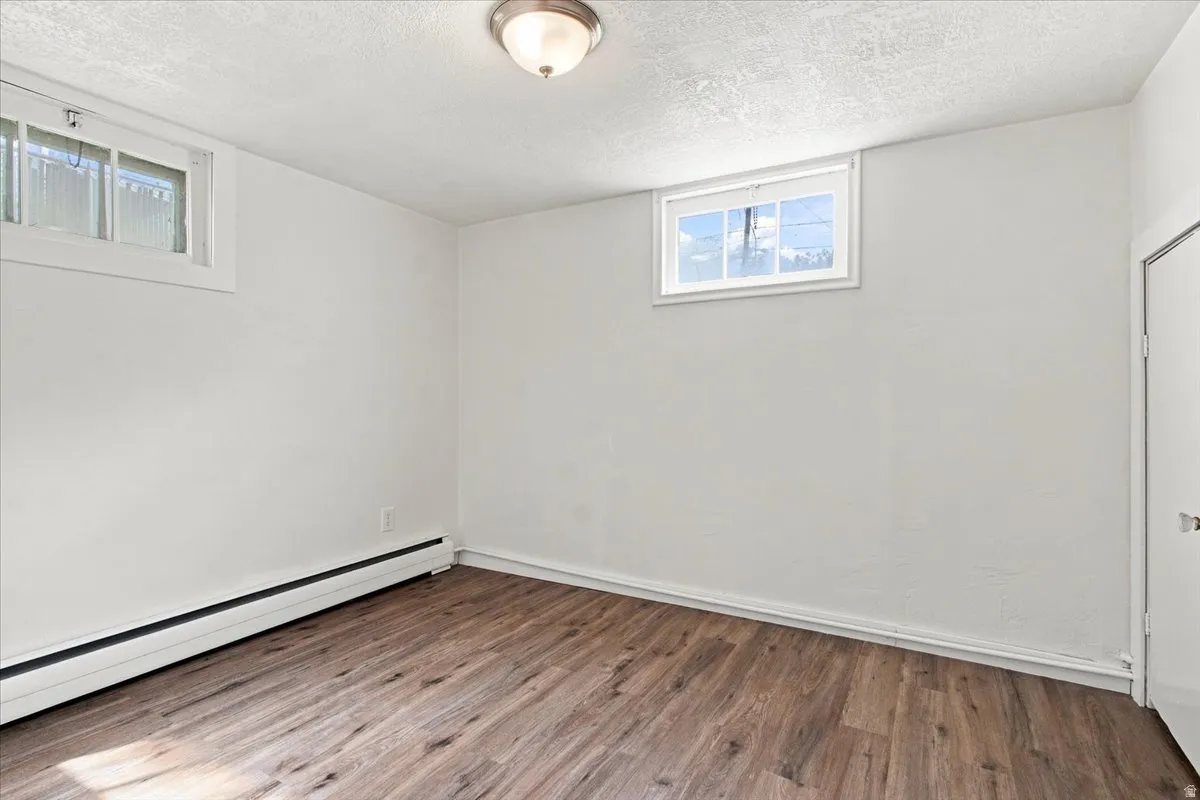 Wood-finish flooring, white walls, two windows, and a flush-mount ceiling light fixture