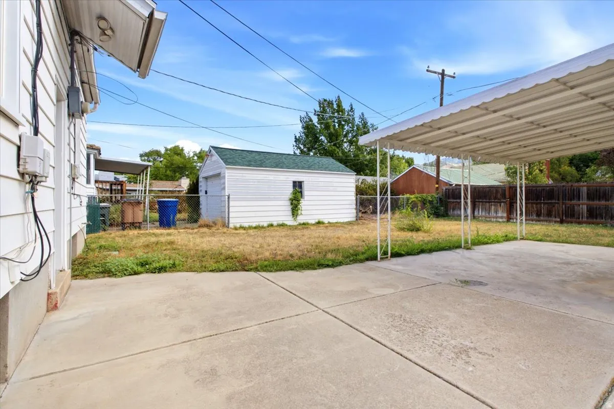 Detached garage structure, concrete patio, and covered carport