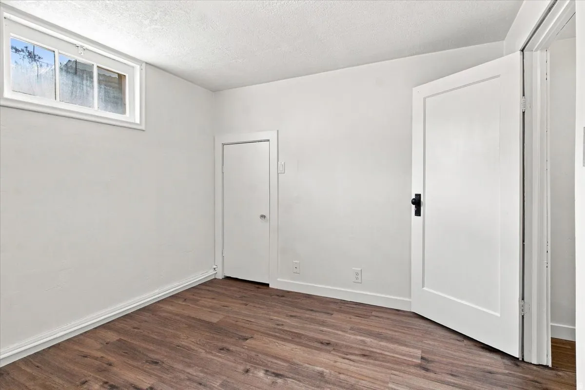 Wood-finish flooring, white paneled doors with dark hardware, and a high-set window