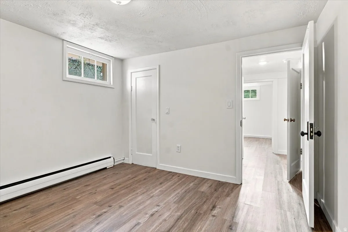Wood-finish flooring, white walls, and a window providing natural light