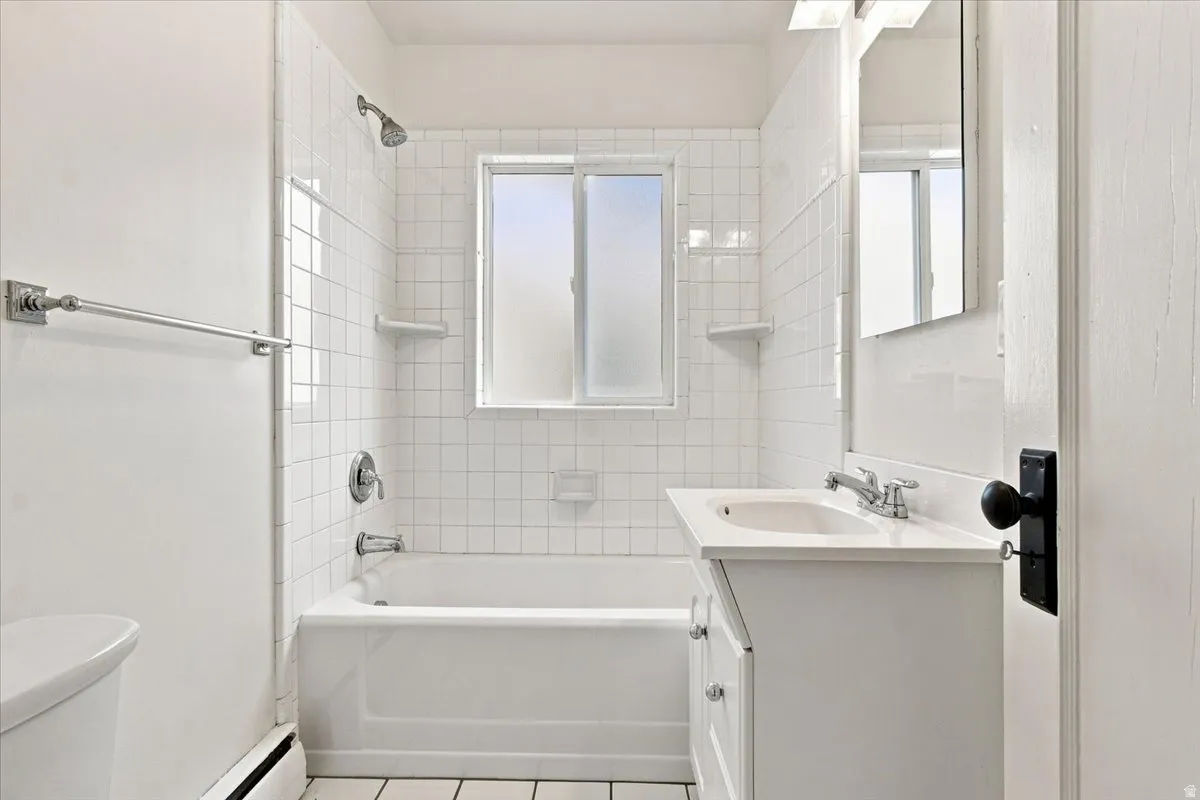 White subway tile surround, built-in bathtub, and a vanity with an integrated sink