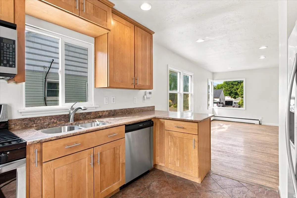 Kitchen featuring wood cabinetry, stainless steel appliances, a double basin sink, and laminate countertops
