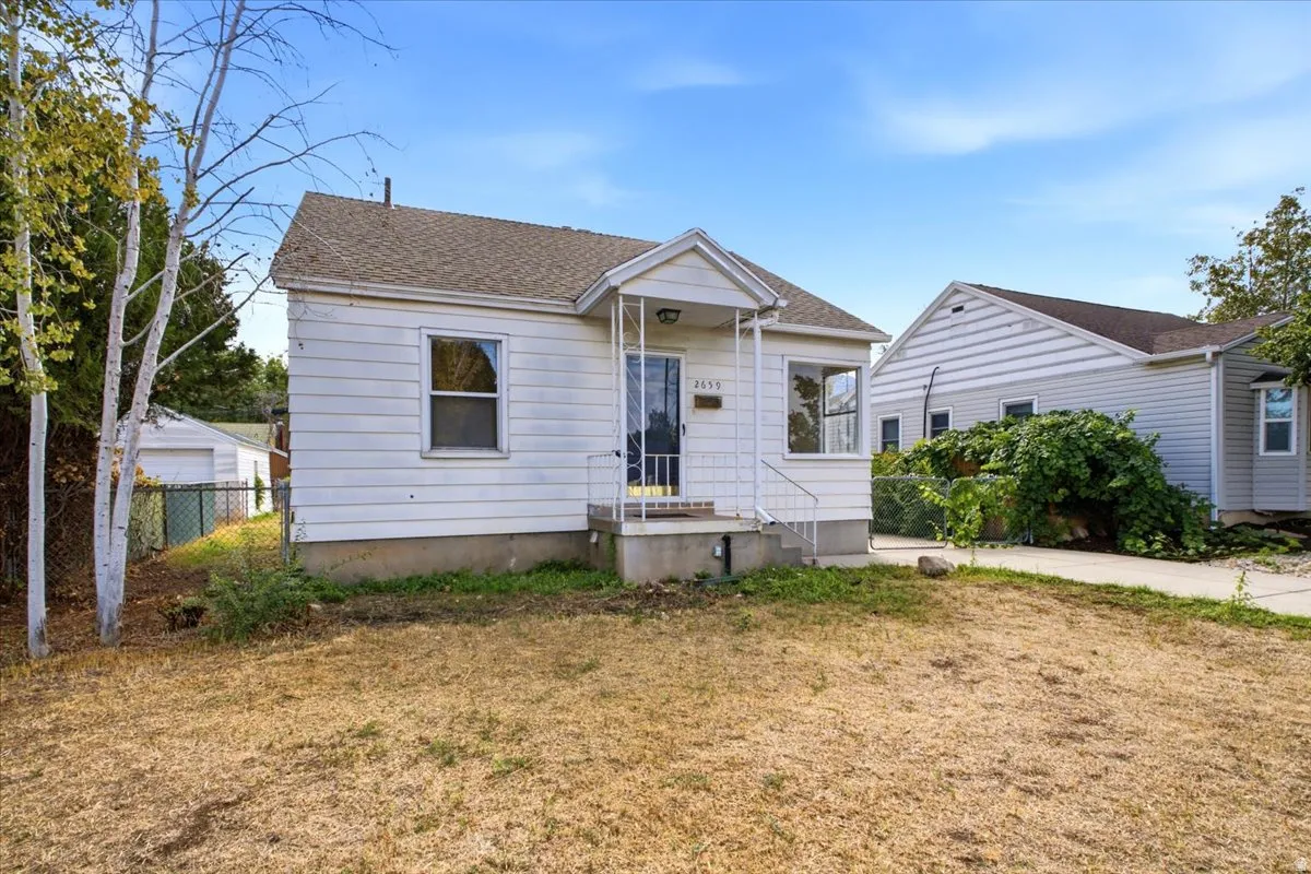 White siding exterior with a covered front entry, bay window, asphalt shingle roof, and concrete foundation
