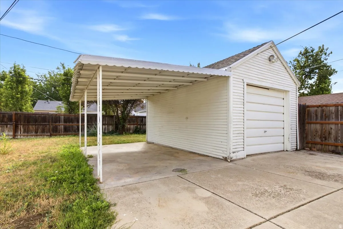 Detached garage with a roll-up door, an attached carport, and a concrete driveway