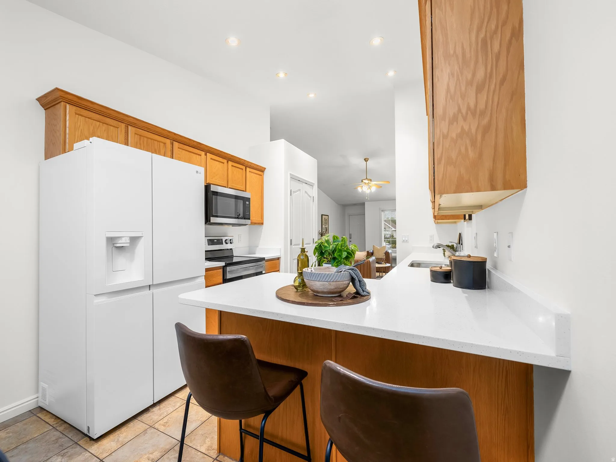 Recessed lighting illuminating the kitchen with wood cabinetry and a white countertop
