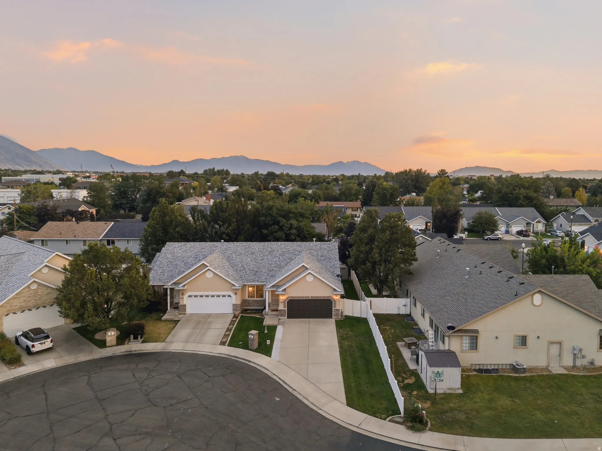 Spacious cul-de-sac property featuring a two-car garage, mature landscaping, and a mountain backdrop