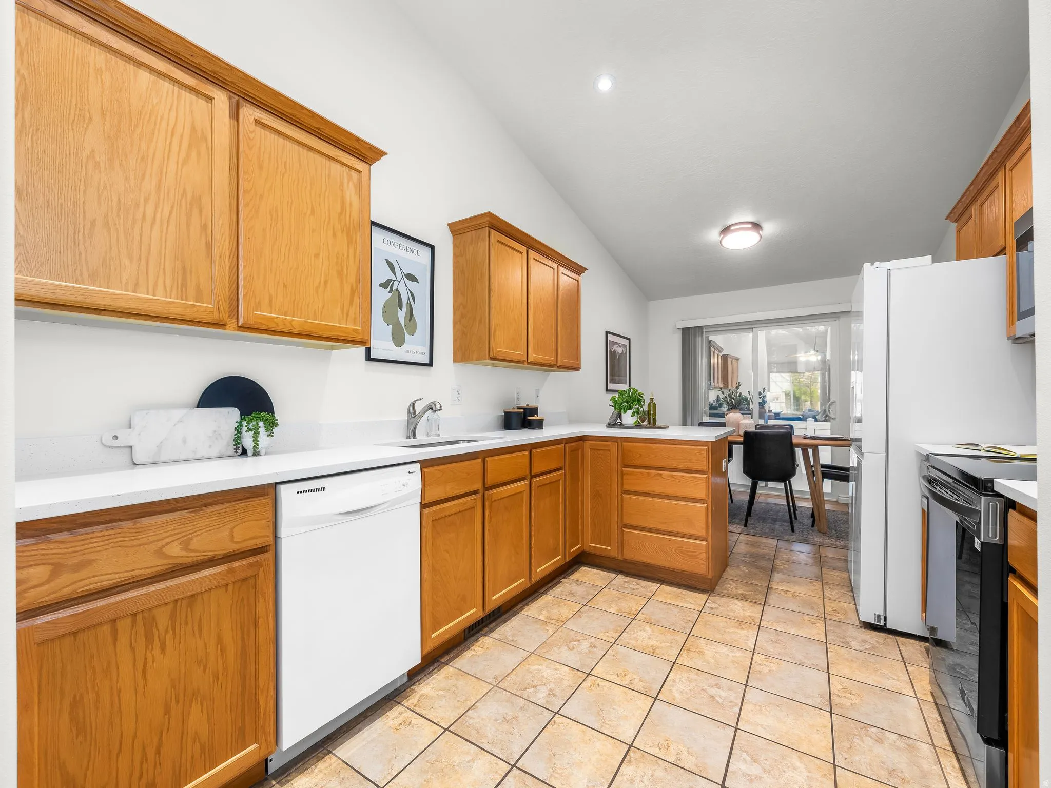 Kitchen featuring wood cabinetry, white countertops, tile flooring, and vaulted ceiling