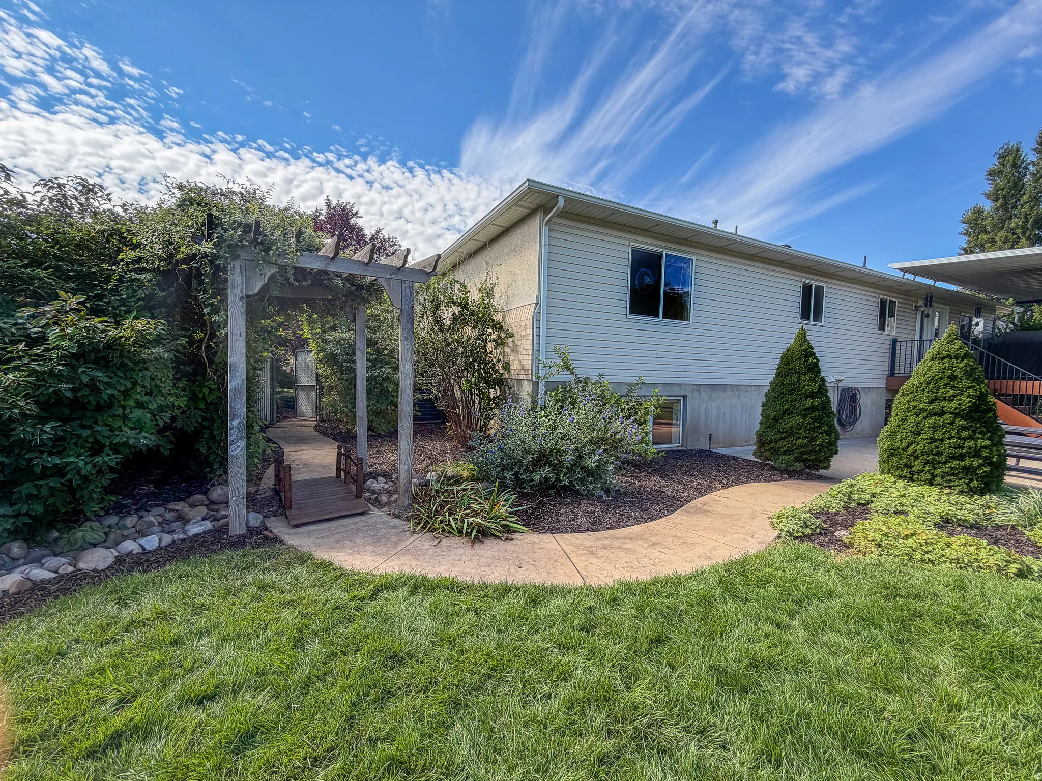 Manicured lawn with a stamped concrete pathway, arbor, and established landscaping