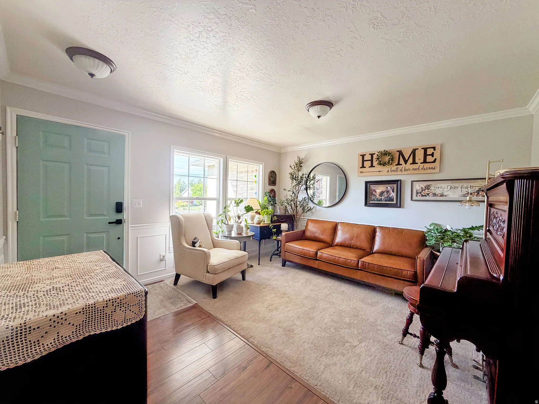 Hardwood-finish flooring, light blue entry door, white wall paneling, crown molding, and recessed lighting