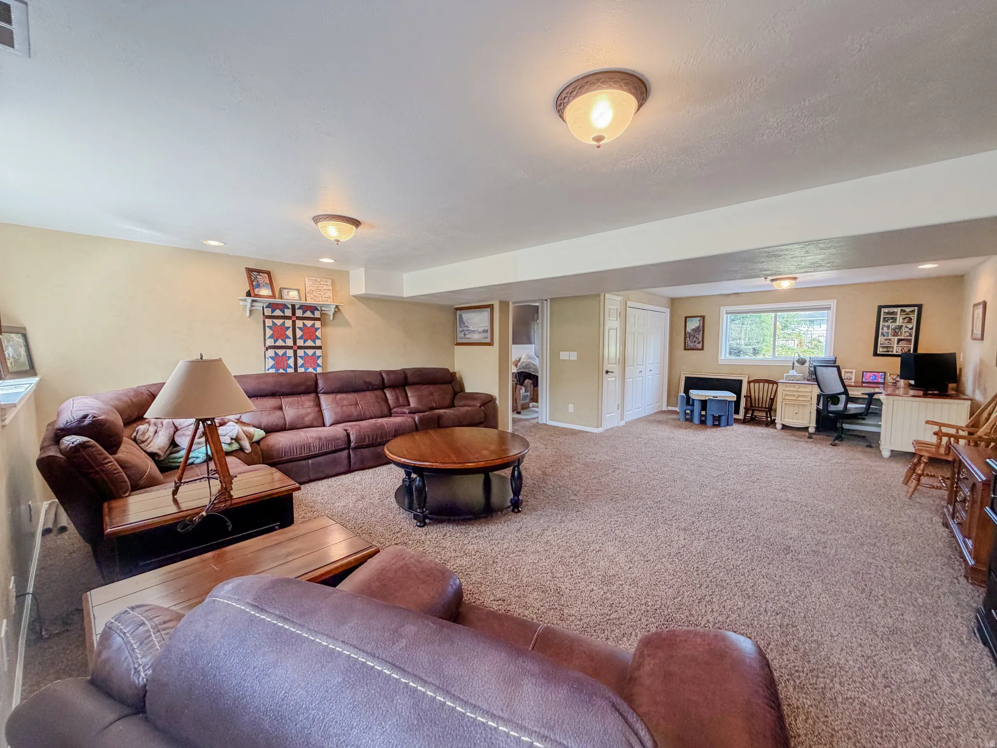 Carpeted living area with recessed lighting, a window, and two permanent doors