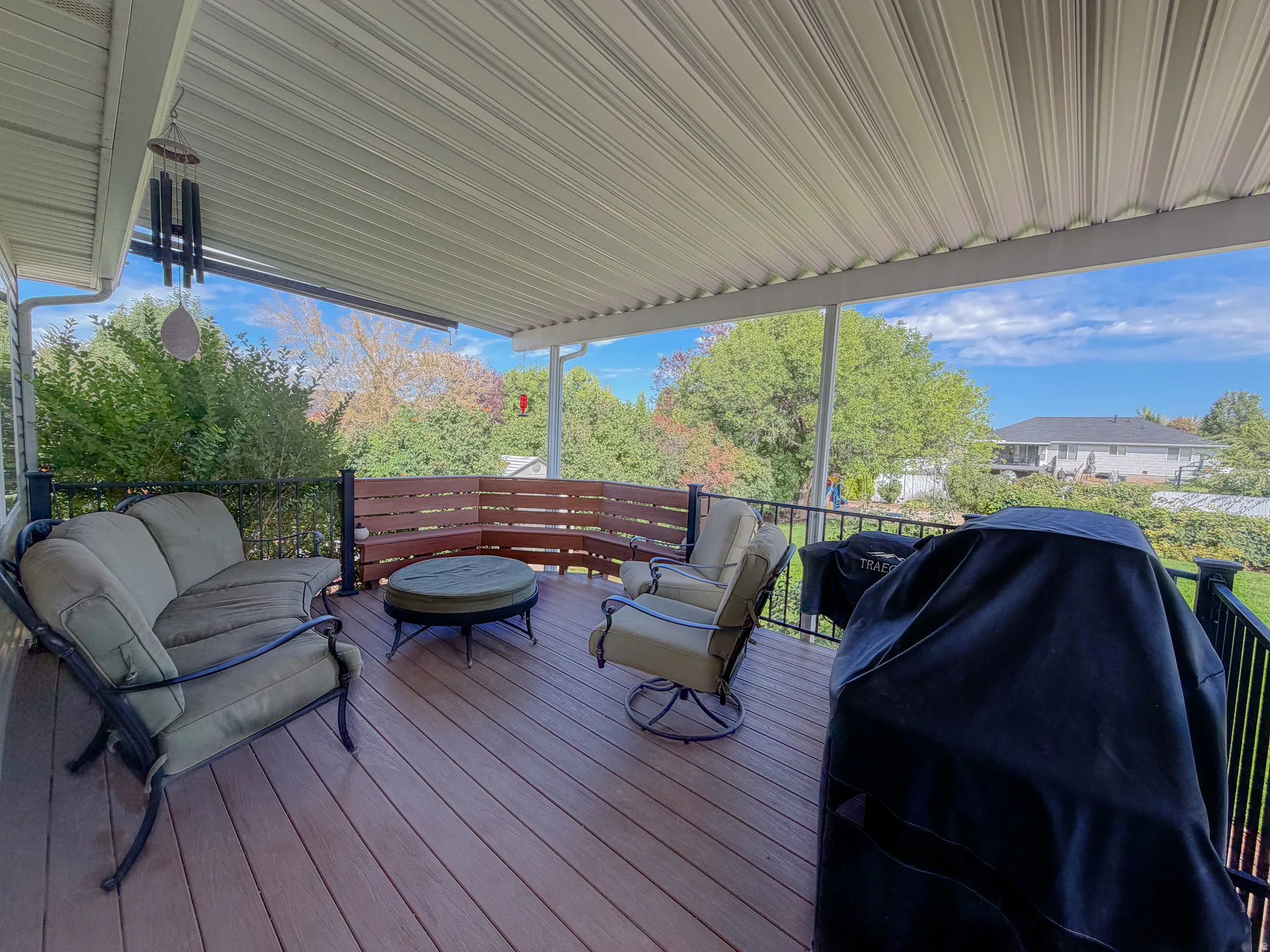 Expansive covered deck featuring wood-finish flooring, black iron railings, and a privacy screen